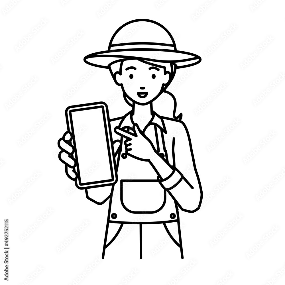 立ってスマートフォンを指差してこちらに向けて見せている農家の女性