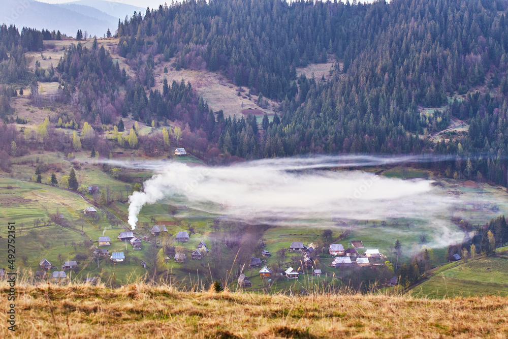 Beautiful spring landscape. Traditional mountain village on hills. Rural Ukraine Carpathian sunrise. Smoke from house