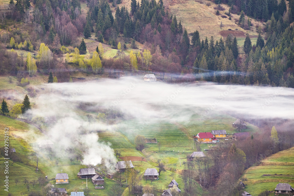 Beautiful spring landscape. Traditional mountain village on hills. Rural Ukraine Carpathian sunrise. Smoke from house