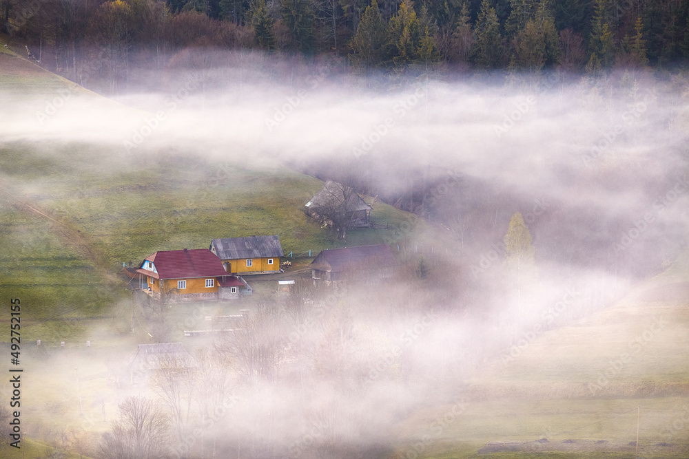Beautiful spring landscape. Traditional mountain village on hills. Rural Ukraine Carpathian sunrise. Smoke from house