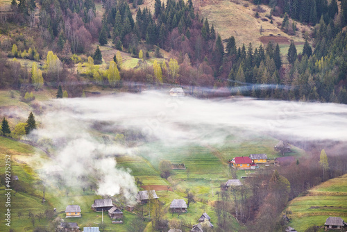 Beautiful spring landscape. Traditional mountain village on hills. Rural Ukraine Carpathian sunrise. Smoke from house