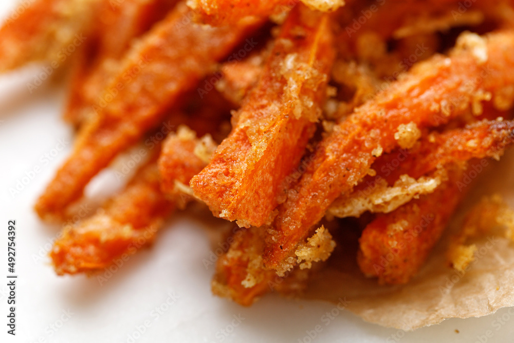 Close up Carrot fries with cheese. Fries baked roasted Sticks of carrots on white table. Organic vegetable Snacks. Close up Carrot fries with cheese. Fries baked roasted Sticks of carrots on white table. Organic vegetable Snacks.
