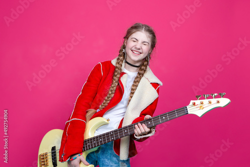 Hobbies and Music Concepts. Expressive Caucasian Guitar Player With Yellow Bass Guitar Posing In Fashionable Fur Red Jacket With Shiny Instrument Over Trendy Pink Background.
