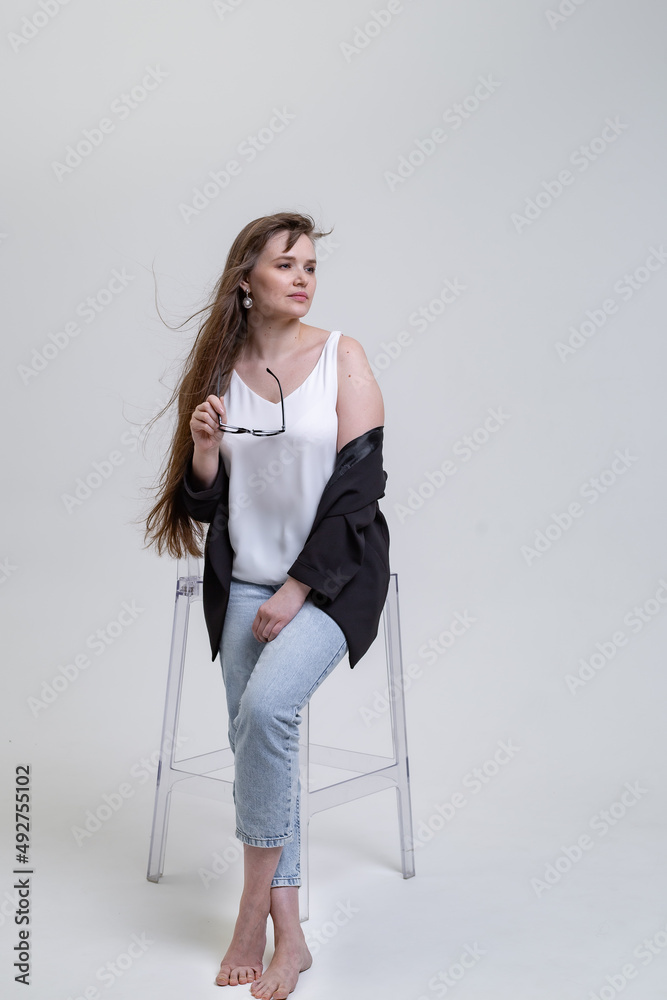 a pretty blonde girl with long hair is sitting on a transparent chair 