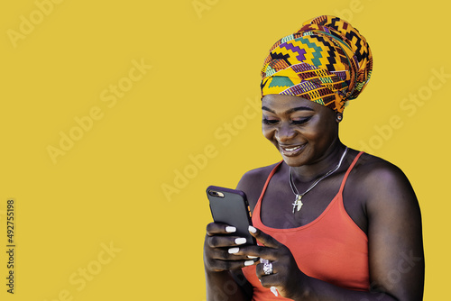 Ghana woman with African colorful headdress standing and chatting with mobile phone, illustrating the wireless technology in today's society photo