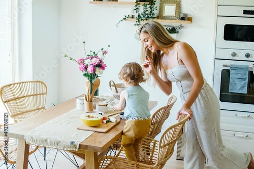 Young beautiful mother spending time with baby daughter in dining room at home.