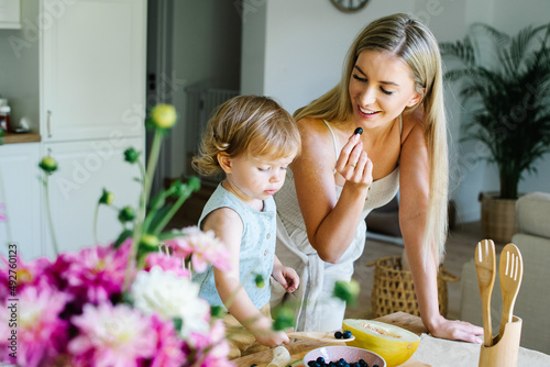 Young beautiful mother spending time with baby daughter in dining room at home.