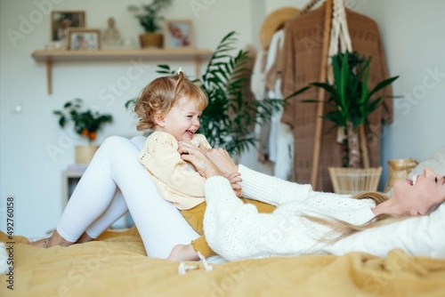 Young beautiful mother playing with baby daughter at home.