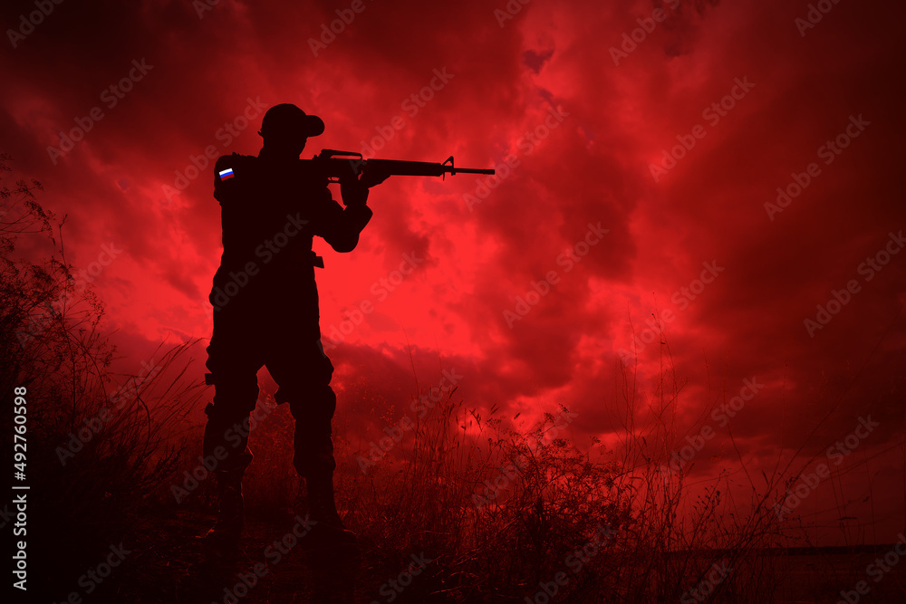 Russian invasion of Ukraine. Silhouette of armed soldier from Russia outdoors, toned in red Russian invasion of Ukraine. Silhouette of armed soldier from Russia outdoors, toned in red