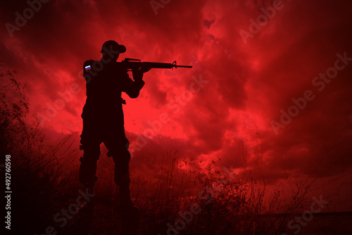 Russian invasion of Ukraine. Silhouette of armed soldier from Russia outdoors, toned in red