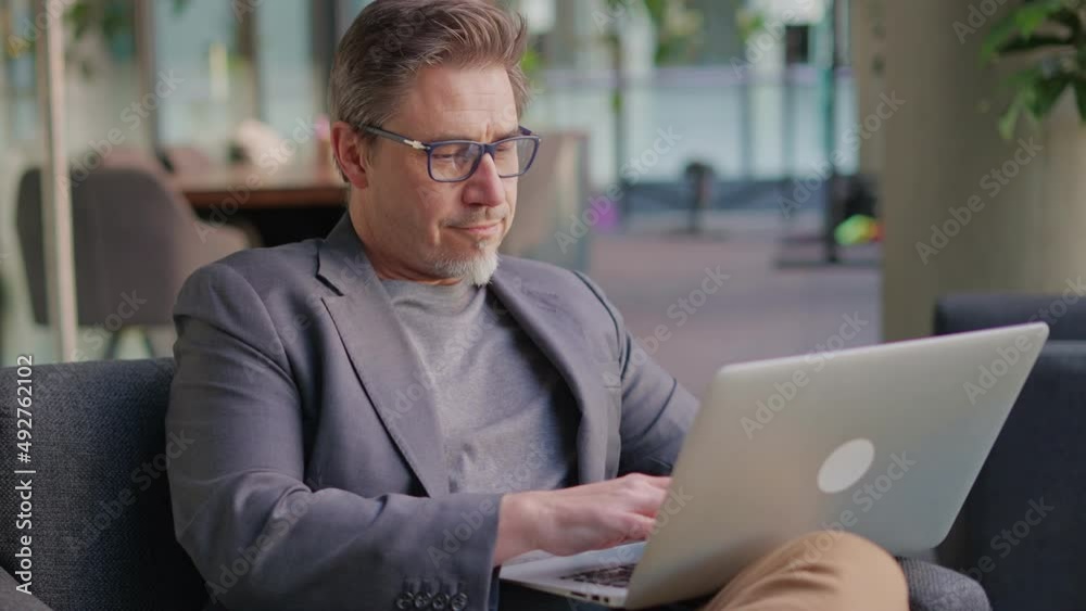 Businessman using laptop computer in office lobby or on cafe terrace. Happy middle aged man, entrepreneur, small business owner working online. Businessman using laptop computer in office lobby or on cafe terrace. Happy middle aged man, entrepreneur, small business owner working online.