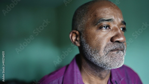 A thoughtful African man in bedroom thinking about life during middle life 50s