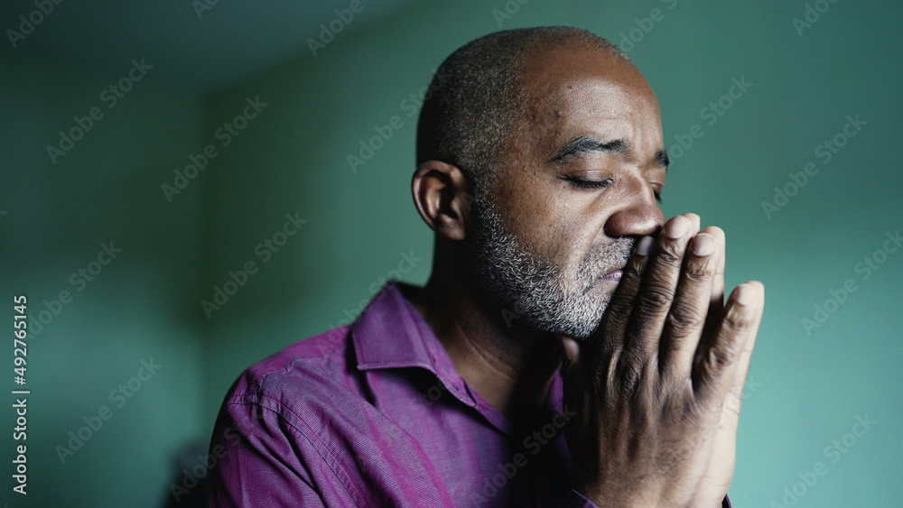 A south american senior black man praying to God