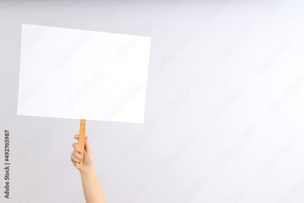 Hand holds protest sign on light background Hand holds protest sign on light background