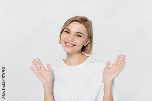 Happy blonde woman waving hands isolated on grey.