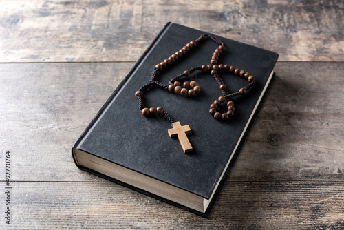 Rosary catholic cross on holy bible on wooden table photo