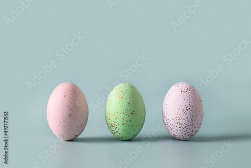 Three decorative pastel eggs on blue background. Happy Easter greeting card with copy space.