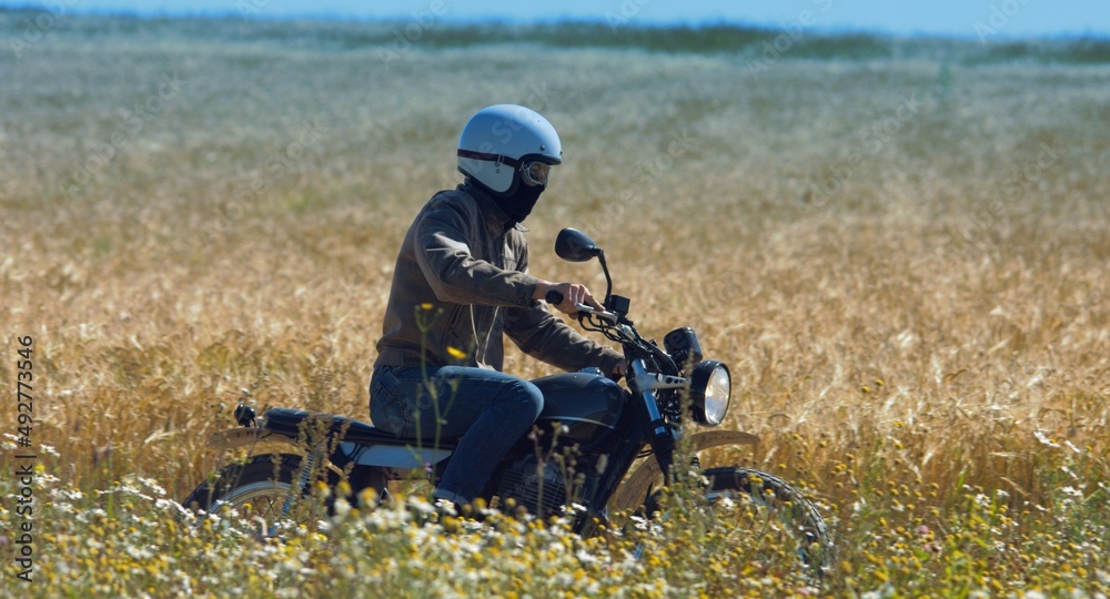 motorcyclist rides through a beautiful field motorcyclist rides through a beautiful field