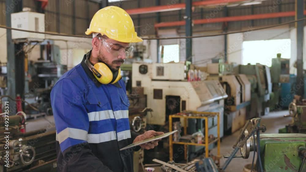 the inspector engineer is checking size of metal part.. the factory worker is recording data on digital tablet. the operator wearing safety equipment with goggle glasses.  