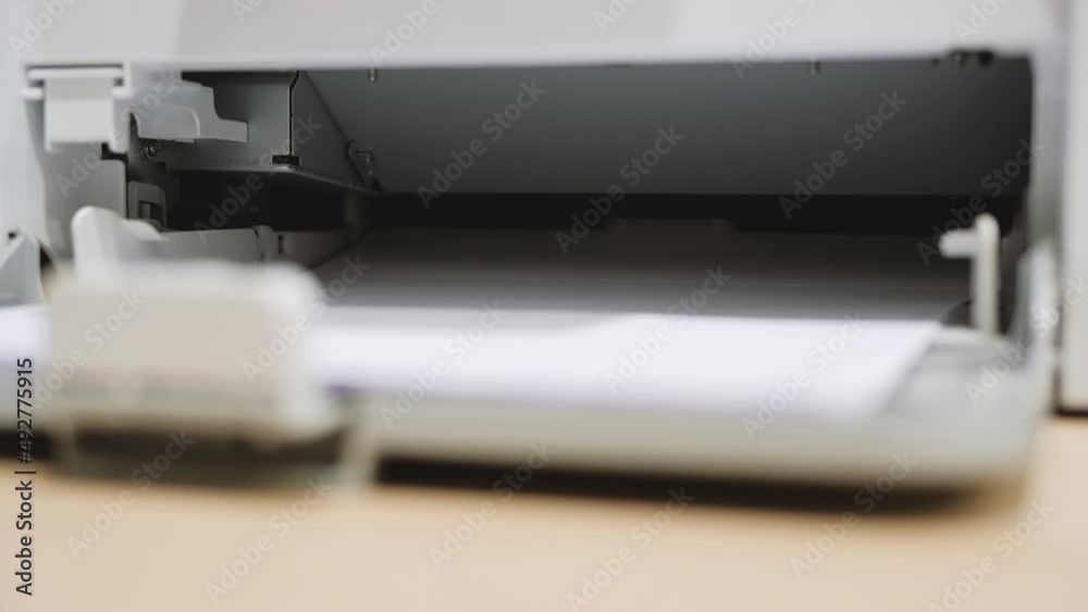Printing document paper with laser printer close up. Laser printer at work in office or home. Printing document paper with laser printer close up. Laser printer at work in office or home.