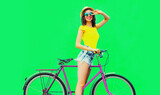 Summer colorful image of happy smiling young woman with bicycle on vivid green background