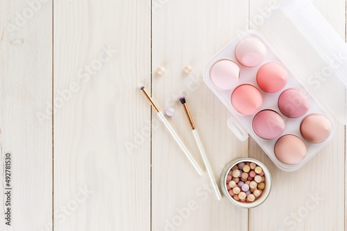 Cosmetic sponges, brushes and powder on a wooden table. Horizontal orientation, top view, copy space.