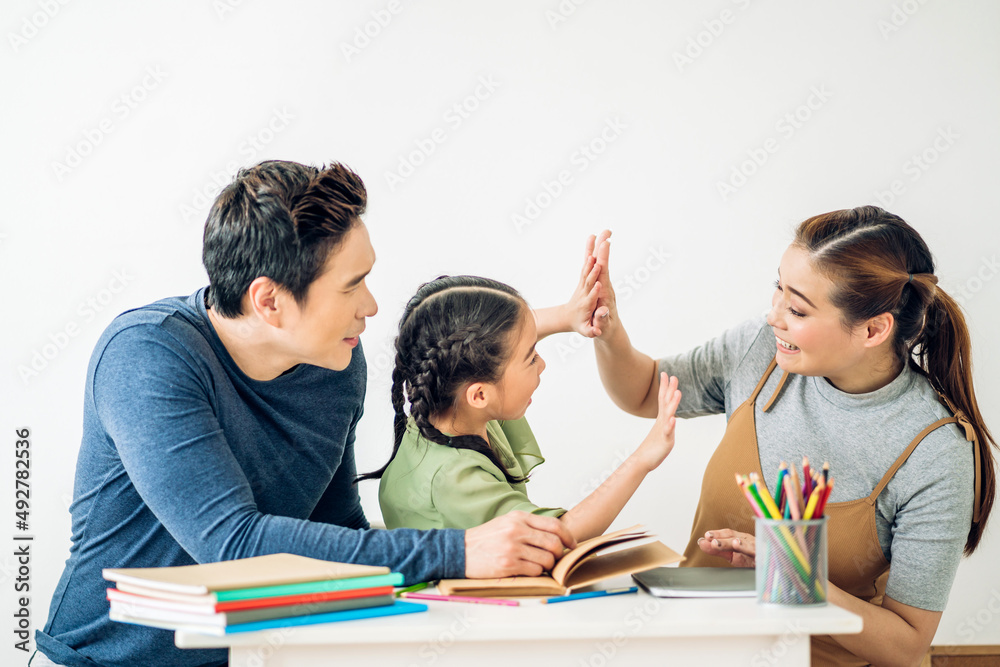 Portrait enjoy happy love asian family father and mother with little asian girl learn and study on table.Mom and dad with asian girl writing with book make homework in homeschool at home.Education Portrait enjoy happy love asian family father and mother with little asian girl learn and study on table.Mom and dad with asian girl writing with book make homework in homeschool at home.Education