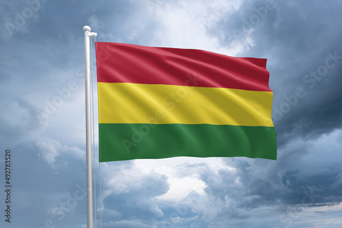 Bolivian flag on a flagpole waving in the wind on a cloudy sky background. Flag of Bolivia photo