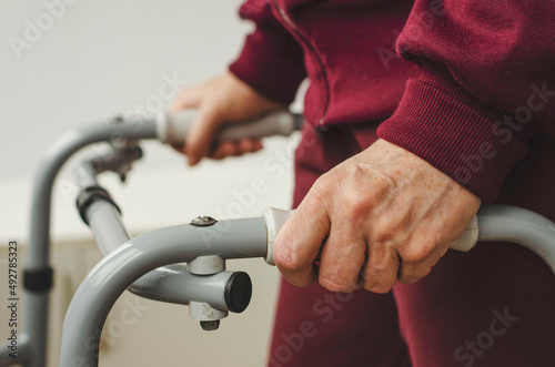 Hands of a senior woman on the handles of a walker. Rehabilitation and healthcare concept.