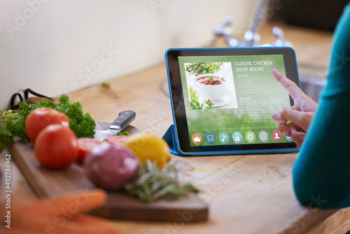 Ooh This one looks nice.... Cropped shot of a young woman looking at an online recipe on her digital tablet while preparing a meal.