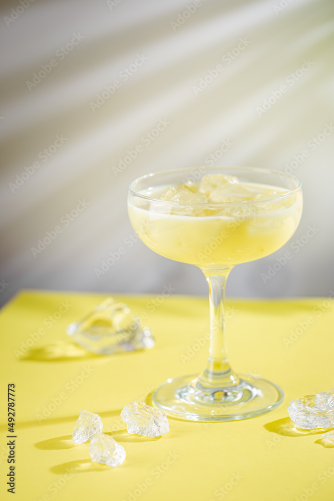 fresh banana and coconut tropical cocktail in a glass over yellow background