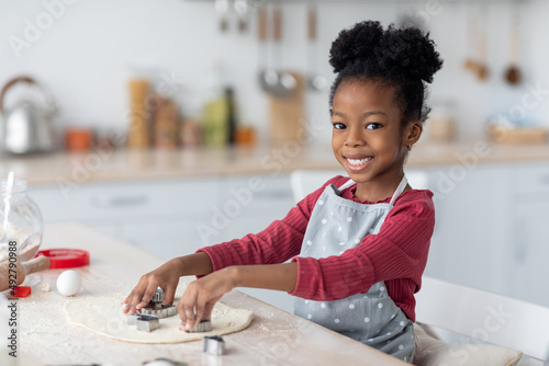 Adorable little black girl making cookies for her family