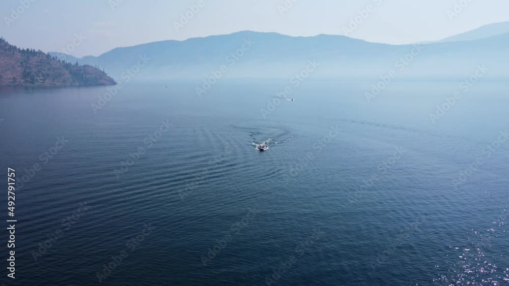 Two speed boats driving over deep, blue Okanagan Lake on a hot summer day in Canada. High aerial pedestal shot Two speed boats driving over deep, blue Okanagan Lake on a hot summer day in Canada. High aerial pedestal shot