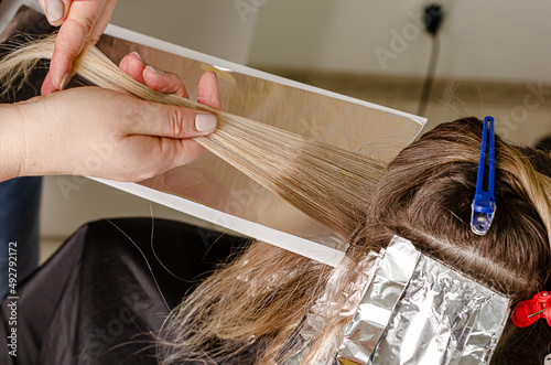 Process of applying bleaching powder on clients hair and wrapping into the foil. AirTouch technique photo