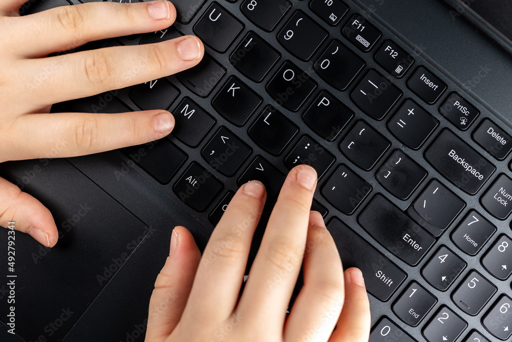Young girl is typing on the keyboard. Risky behaviour of children in internet. Young girl is typing on the keyboard. Risky behaviour of children in internet.