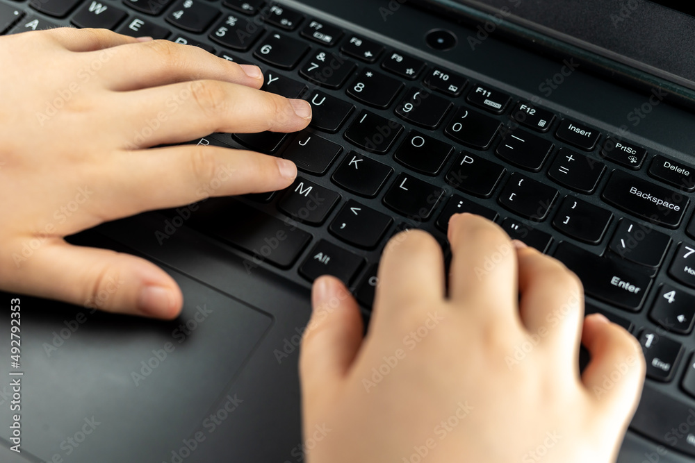 Young girl is typing on the keyboard. Risky behaviour of children in internet. Young girl is typing on the keyboard. Risky behaviour of children in internet.