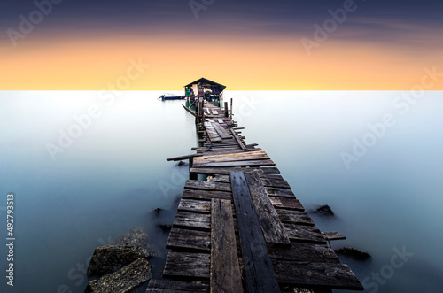Beautiful scenery of an old wooden pier in a minimalist fine art with the view of the sunrise