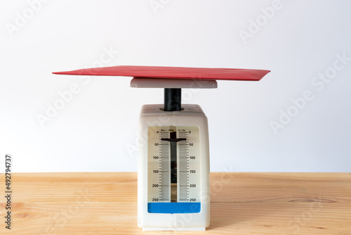 A letter is being weighed on an analogue weighing scale