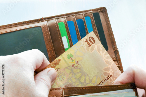 Man hand putting 10 Saudi riyal banknote in the wallet.   photo