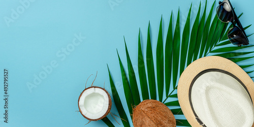 Summer background concept. Hat, sunglasses and coconut on blue background. Flat lay, copy space.