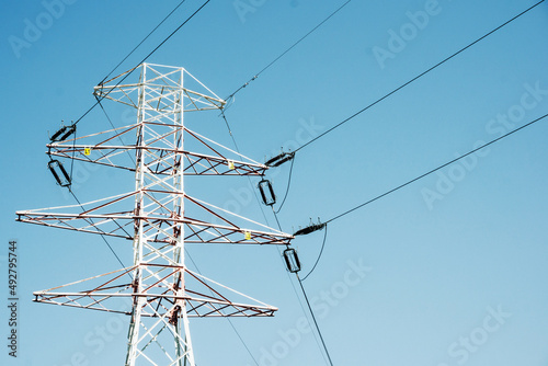 Fototapeta Naklejka Na Ścianę i Meble -  Transmission tower background. High voltage electricity pylon. Metal construction and blue sky. Power lines background. Energy distribution texture. Empty copy space on the side.