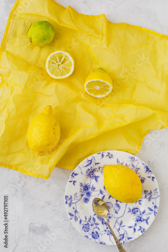 Overhead view of lemons and citrus fruits on a vibrant yellow and white background, summer sensations