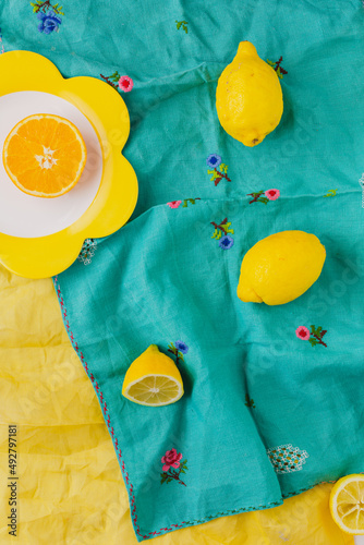 Overhead view of oranges with vintage turquoise tablecloth background and yellow napkin