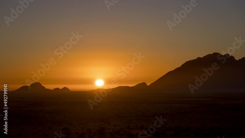 Golden Warm Sunset Over Silhouetted Spitzkoppe Peak In Namibia. Timelapse photo