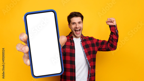 Cheerful guy showing empty smartphone screen gesturing yes