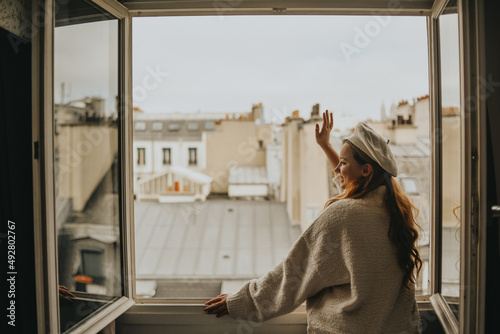 Photography A woman stands near the window against the backdrop of the roofs of Paris