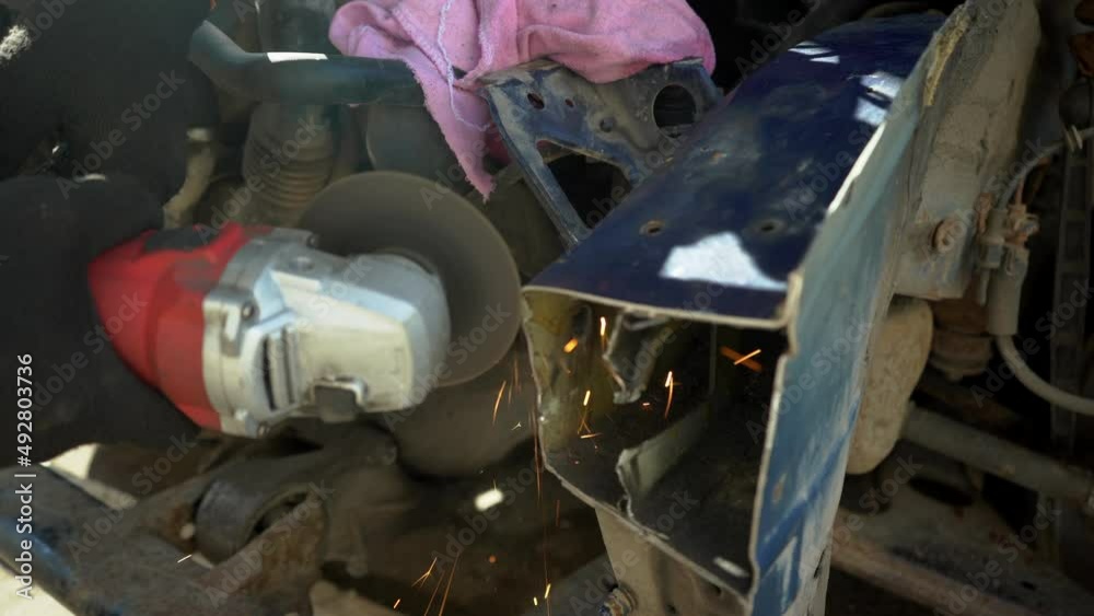 Garage mechanic removing paint with the Angle Grinder before standing