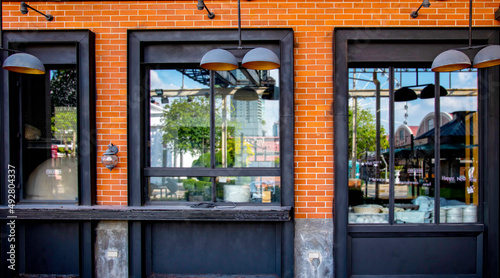 Outdoor mock up of store and shop front template - front view vintage black grey shop tone with blurred windows display,  vintage lamp and orange brick wall.