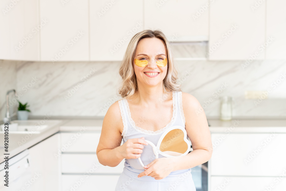 Middle age woman in pajama at kitchen with cosmetic collagen patches under eyes. Facial care. Skin cosmetology. Morning routine, Home spa and wellness, cosmetic procedures, Eye skin treatment Middle age woman in pajama at kitchen with cosmetic collagen patches under eyes. Facial care. Skin cosmetology. Morning routine, Home spa and wellness, cosmetic procedures, Eye skin treatment
