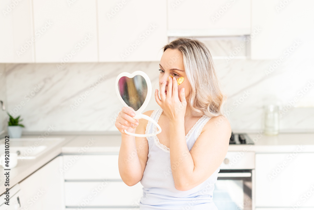 Middle age woman in pajama at kitchen with cosmetic collagen patches under eyes. Facial care. Skin cosmetology. Morning routine, Home spa and wellness, cosmetic procedures, Eye skin treatment Middle age woman in pajama at kitchen with cosmetic collagen patches under eyes. Facial care. Skin cosmetology. Morning routine, Home spa and wellness, cosmetic procedures, Eye skin treatment
